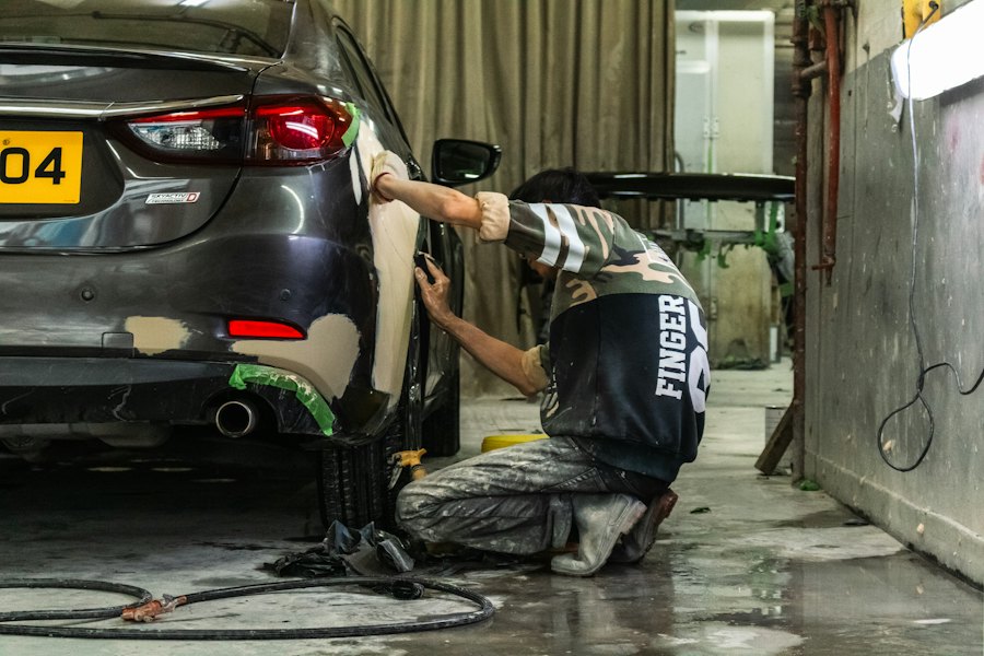 Carrozziere al lavoro sul paraurti di un'auto